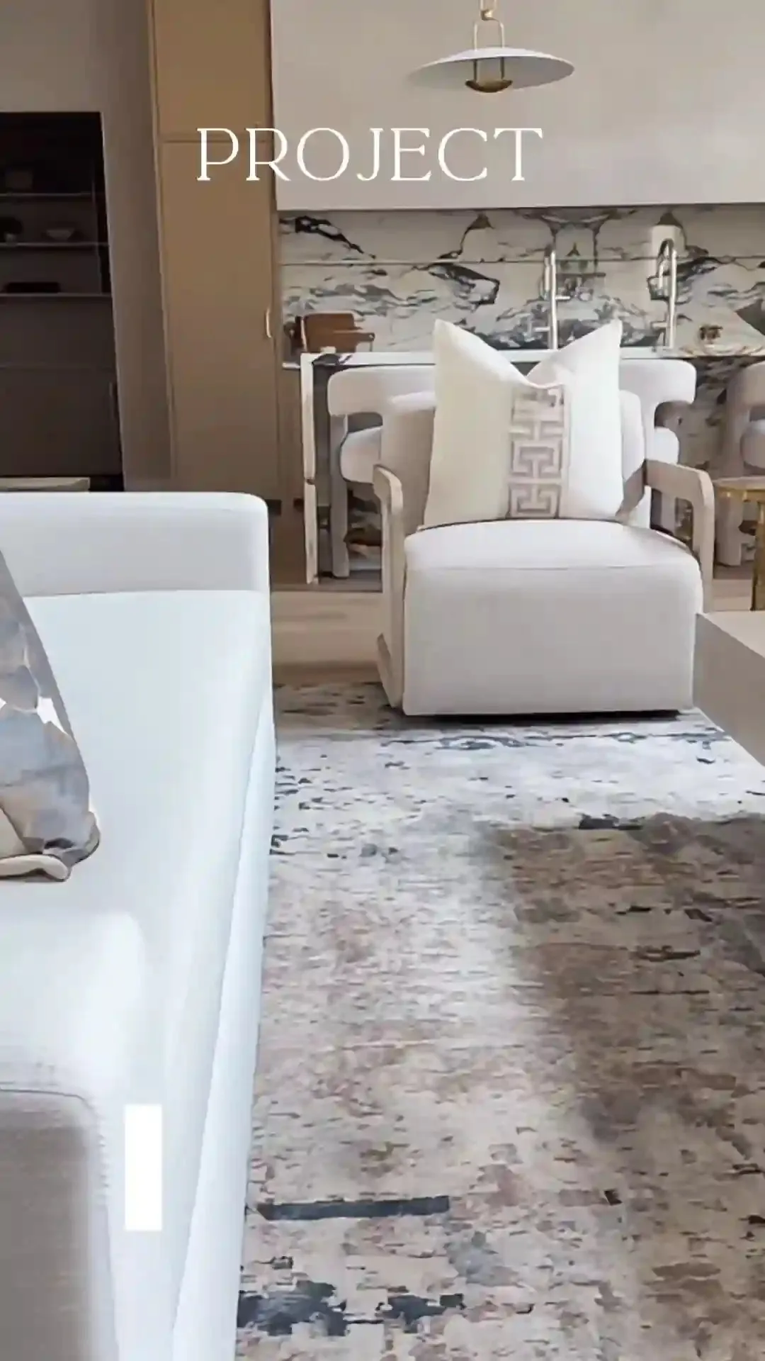 Luxe Design Group reel cover: “Project” in serif type over a staged room with a cream swivel chair, a marble backsplash and an abstract rug.