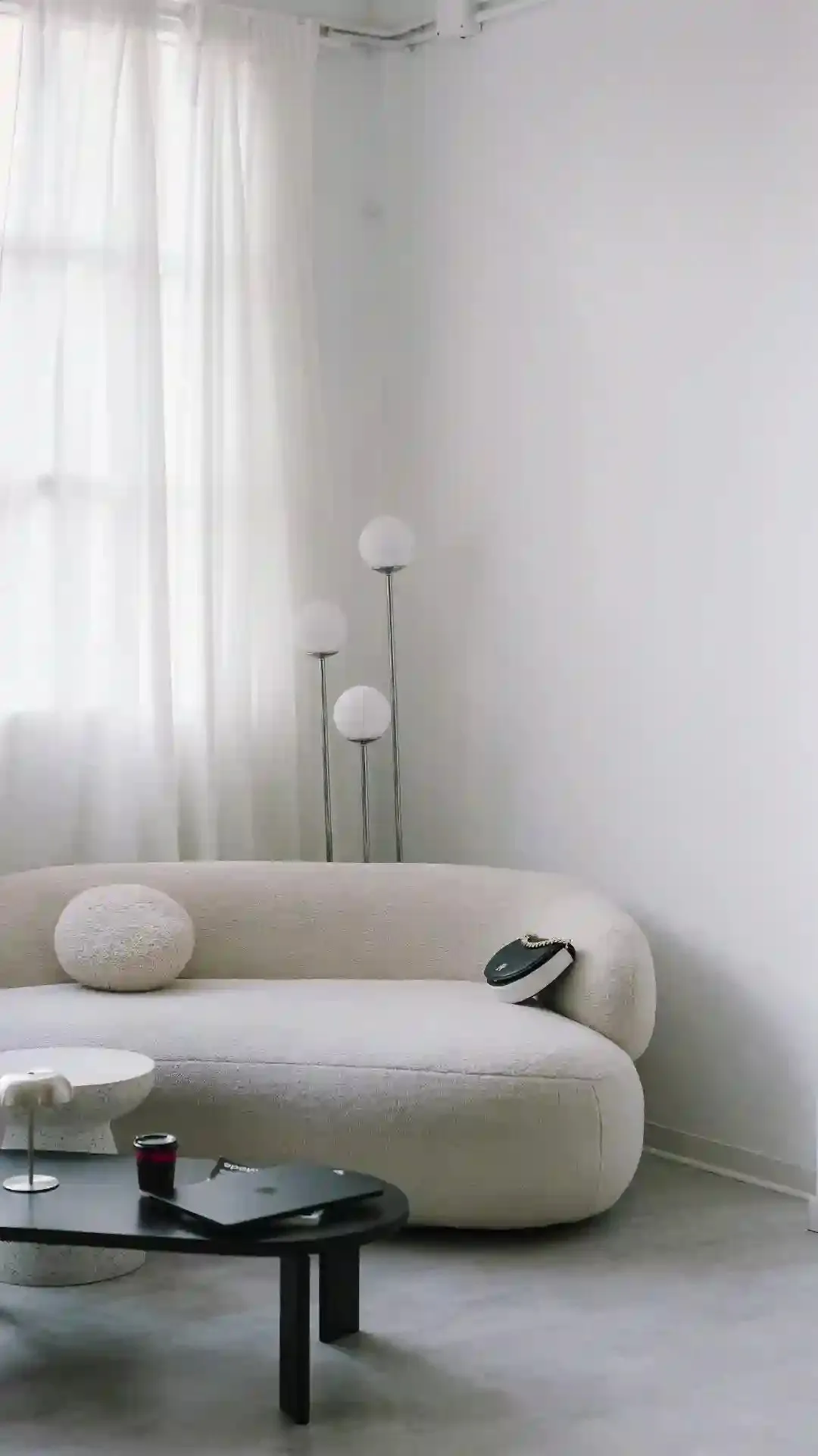 Luxe Design Group story: a curved bouclé sofa, a low black coffee table and a globe floor lamp in a bright, minimal room.